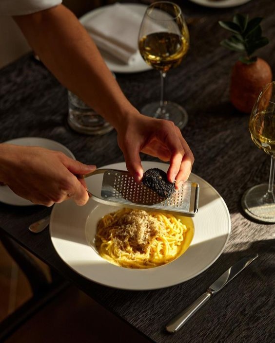 Chef grating truffle over pasta